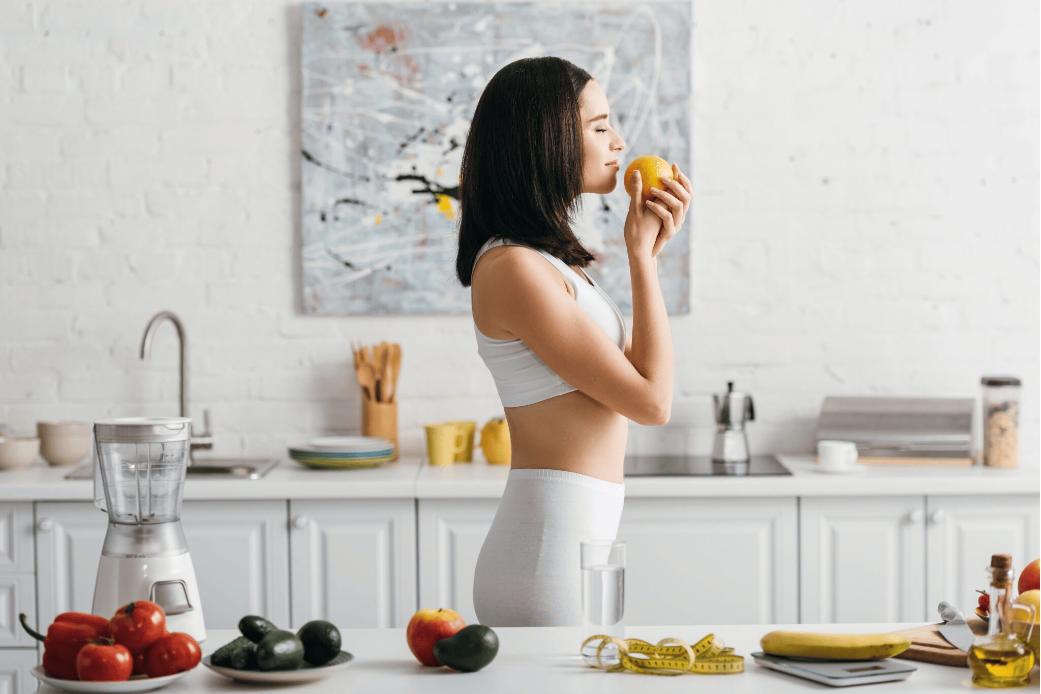 Chica oliendo una fruta en la cocina.
